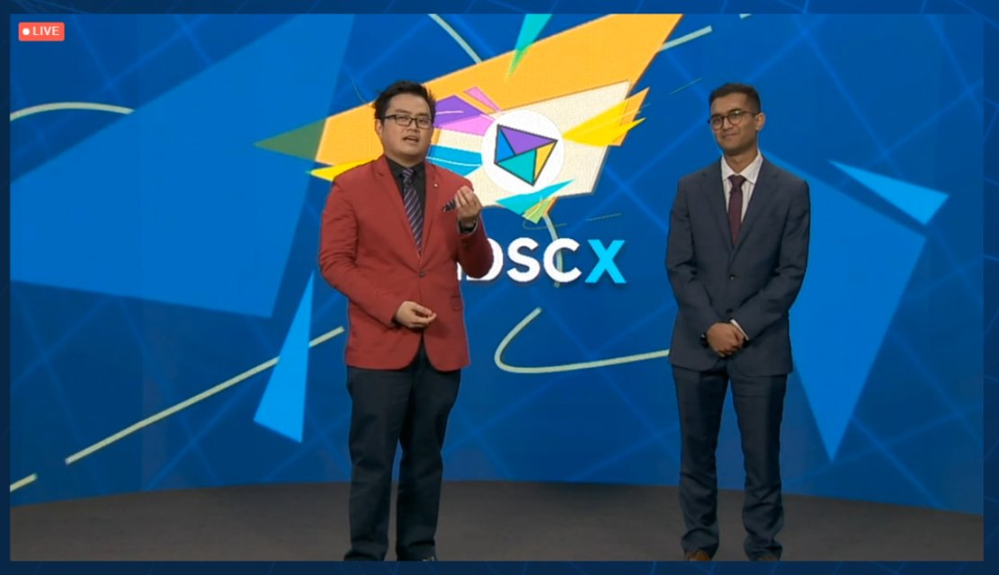 MDSCx Hosts stand in front of a LED screen